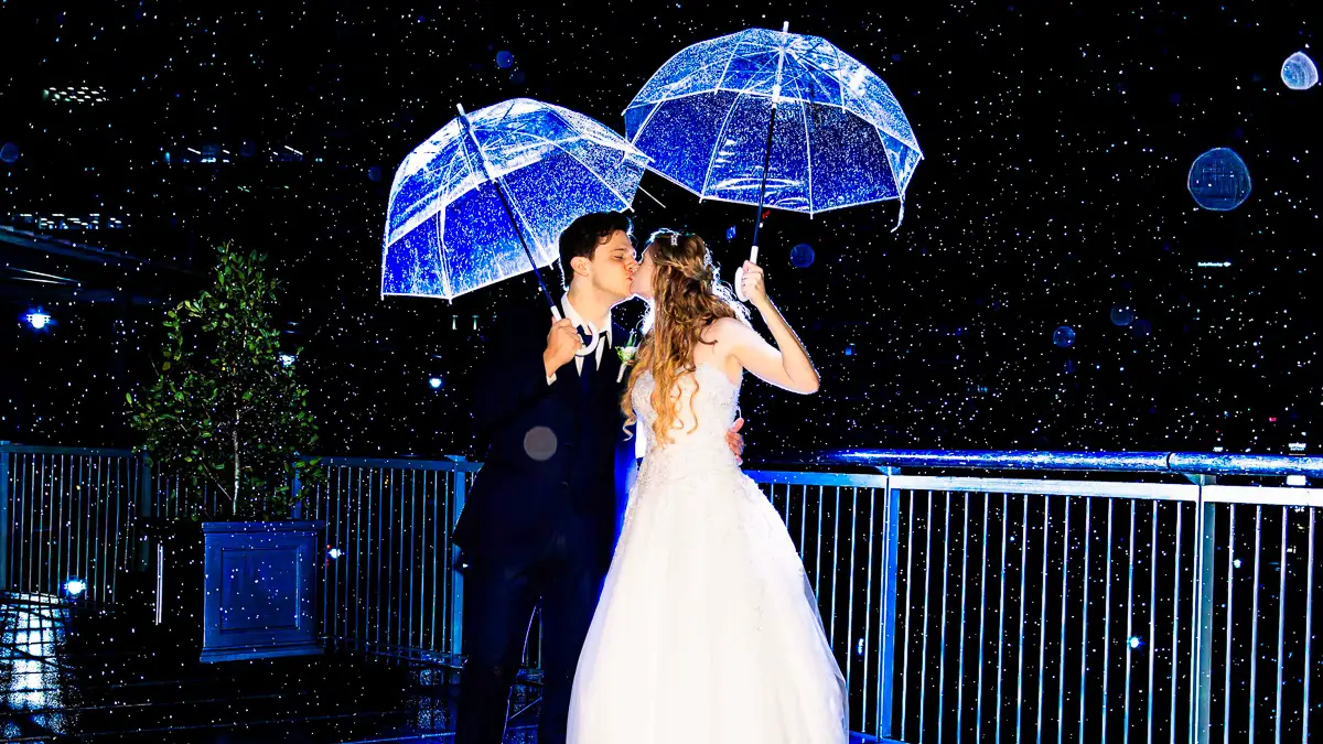 Book your wedding photography for a magical rainy dance under glowing umbrellas at night.