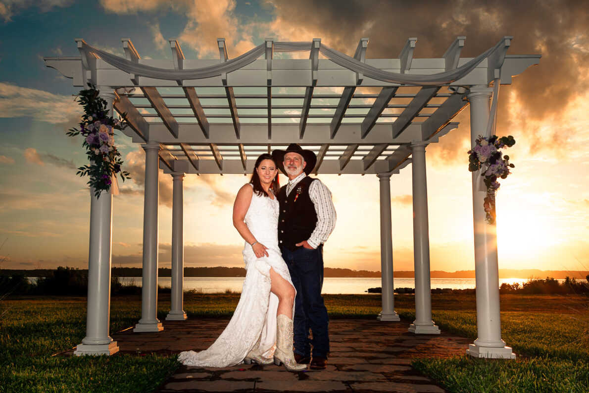 A bride and groom standing under a pergola at sunset, showcasing elegant wedding photography.