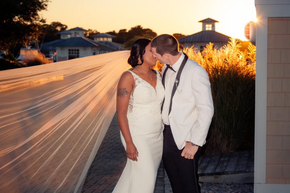 Bride and groom sharing an intimate moment as the bride’s veil flows in the golden sunset.