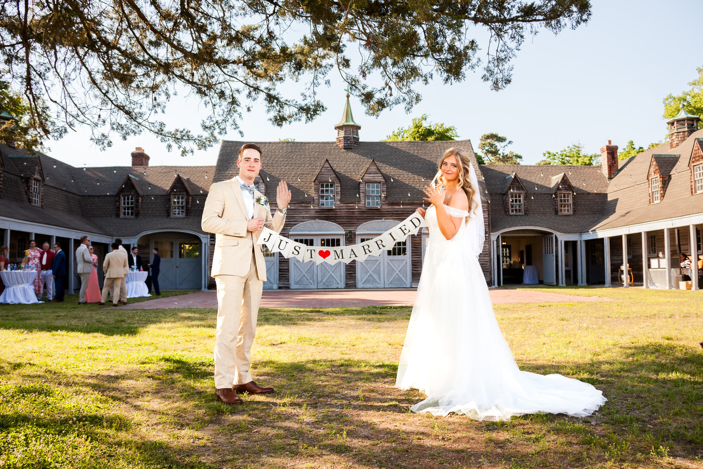 Madison and Hunter holding a Just Married banner and showing their wedding rings at Flyway Lodge